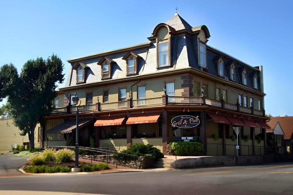 Three-story historic building with dormer windows and a "Grill & Pub" sign on the front, situated on a street corner with landscaping and outdoor seating—an inviting spot popular among Gettysburg wedding venues.